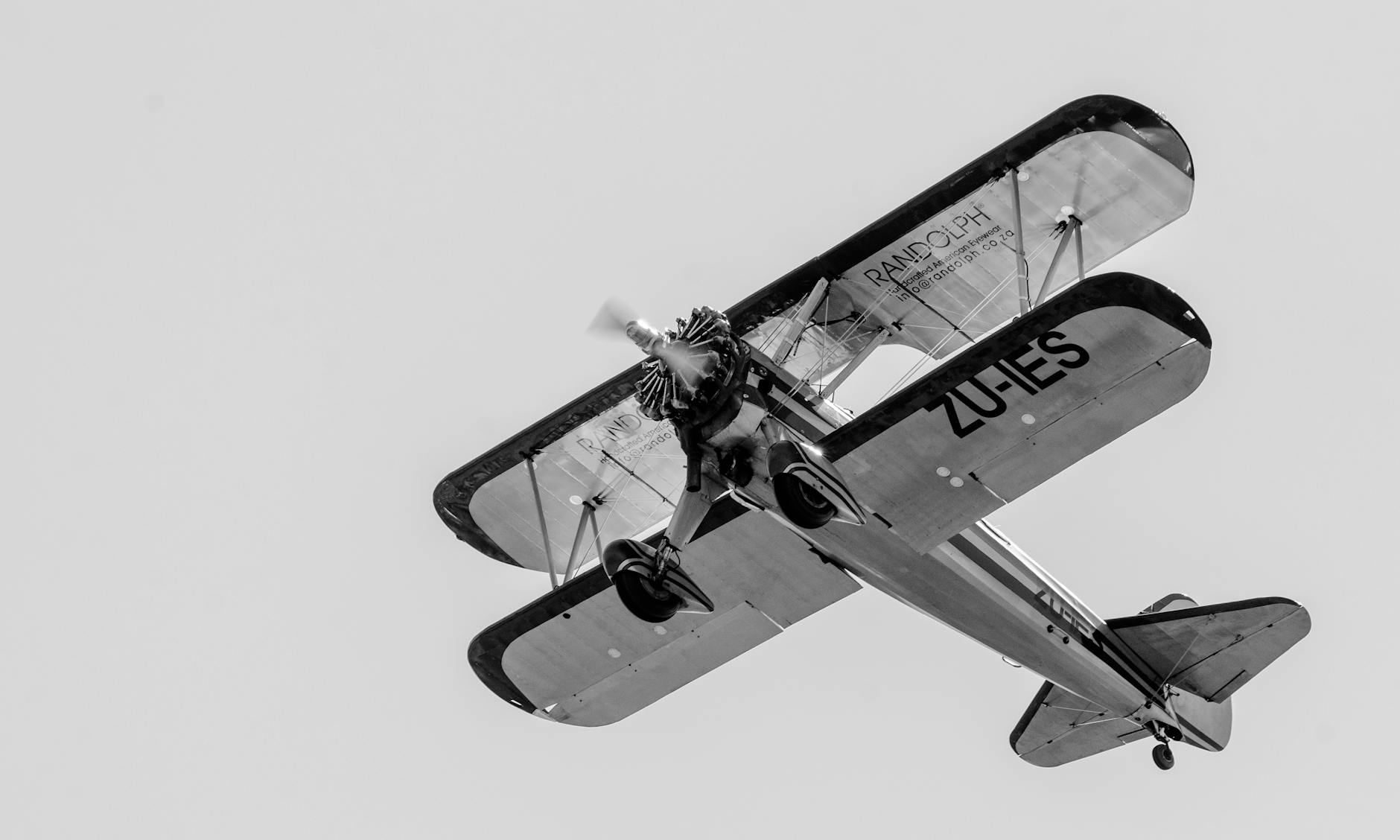 grayscale photo of a biplane flying in the sky